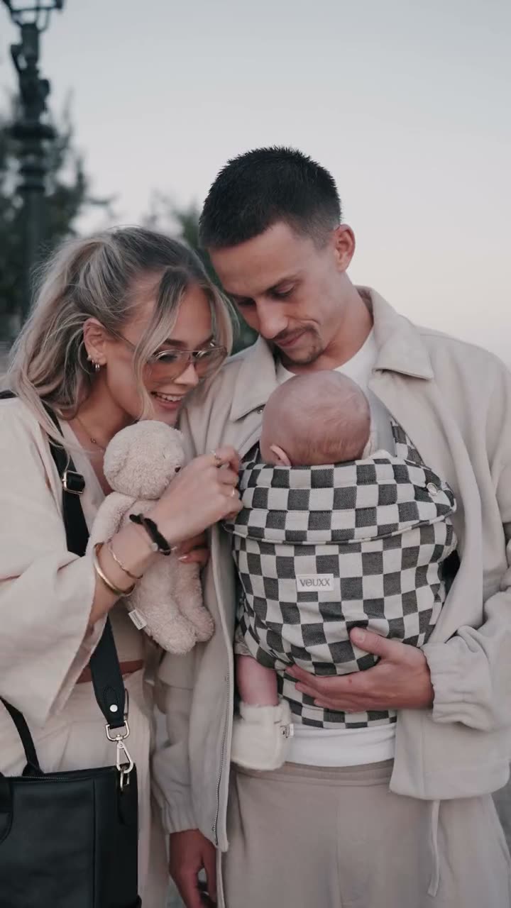 Jonge ouders met hun baby in een VOUXX draagzak met ruitpatroon